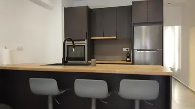a kitchen with a counter with four chairs and a refrigerator at L apartment2 in Athens