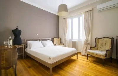 a bedroom with a bed and a chair and a window at Emporikon Apartment Steps From Historic Center in Athens