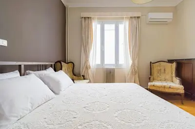 a bedroom with a large white bed and two chairs at Emporikon Apartment Steps From Historic Center in Athens