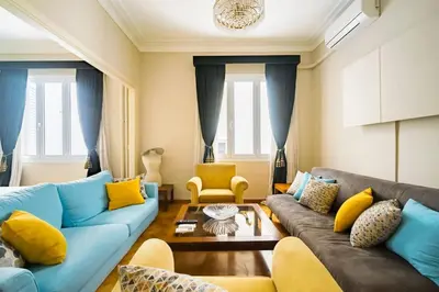 a living room with a blue couch and yellow pillows at Emporikon Apartment Steps From Historic Center in Athens