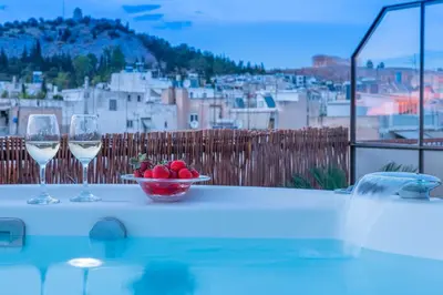 two glasses of wine and a bowl of fruit on a table at TopFloor Getaway Balcony&Hot tub+Acropolis view in Athens