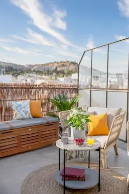 a patio with a couch and a table on a balcony at TopFloor Getaway Balcony&Hot tub+Acropolis view in Athens