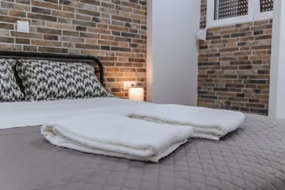 a bed with white blankets on it with a brick wall at Niovis Loft VIPGreece in Athens