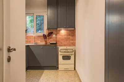 a kitchen with black cabinets and a white stove at Acropolis View-Living Stone Amethyst in Athens