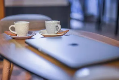 two coffee cups on a table with a laptop at Nueva Era Boutique in Athens