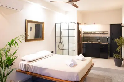 a bedroom with a bed with a mirror and a kitchen at Mosaics studio apt in the Central Market of Athens in Athens