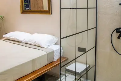 a bedroom with a bed and a glass shower door at Mosaics studio apt in the Central Market of Athens in Athens