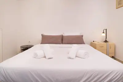 a white bed with white pillows on top of it at Spacious Modern Apartments With Great Rooftop View in Athens
