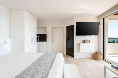 a white bedroom with a large bed and a flat screen tv at Athens Riviera Bay View Suite By The Olon in Athens