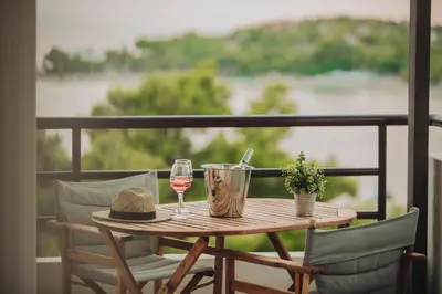 a wooden table with two glasses of wine on a balcony at Athens Riviera Bay View Suite By The Olon in Athens