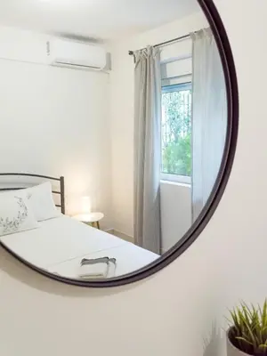a mirror in a bedroom with a bed and a window at Easy & Comfy Nights in Athens