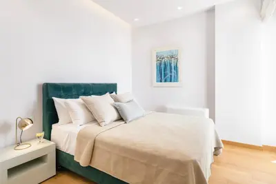a white bedroom with a bed with white sheets and pillows at Divine Residence, a SeaView Retreat, By ThinkVilla in Piraeus