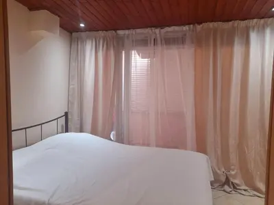 a bedroom with a white bed and a window at Cozy apartment in Piraeus