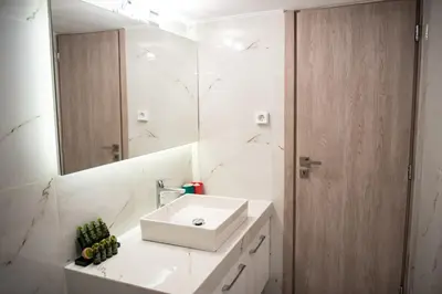 a white bathroom with a sink and a mirror at Renovated apartment 5min from subway station 'Attiki' in Athens
