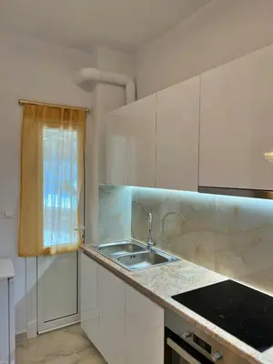 a kitchen with white cabinets and a sink and a window at Apollonion Luxury Apartment near the metro station in Athens