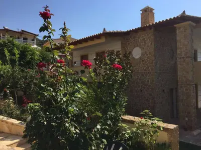 a house with red roses in front of it at Platanus Gardenhouse in Anavissos