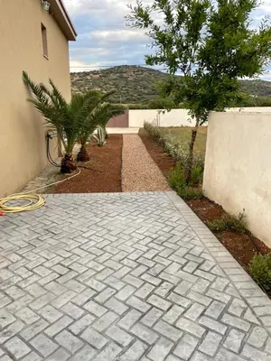 a brick walkway next to a building with a tree at Saint George family house in Palaiá Fókaia