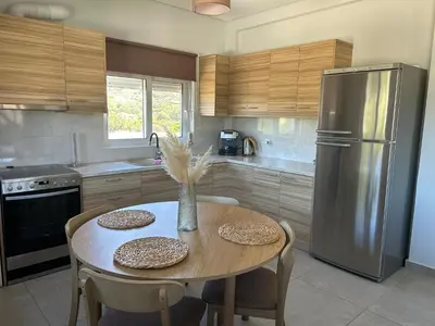 a kitchen with a table and a stainless steel refrigerator at Saint George family house in Palaiá Fókaia