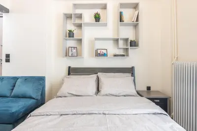 a bedroom with a bed and a blue couch at ANO PATISIA STUDIO (ΑΓΙΟΣ ΕΛΕΥΘΕΡΙΟΣ) in Athens