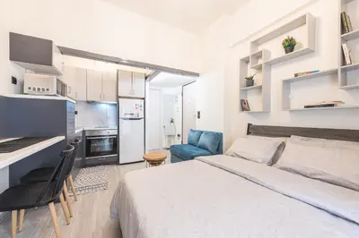 a bedroom with a bed and a desk and a kitchen at ANO PATISIA STUDIO (ΑΓΙΟΣ ΕΛΕΥΘΕΡΙΟΣ) in Athens