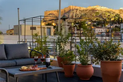 a patio with a table with wine glasses and plants at Meno Suite with Private Terrace - Jaccuzzi, Acropolis View in Athens