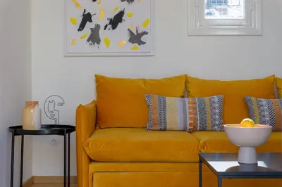 a yellow couch in a living room with a table at Meno Suite with Private Terrace - Jaccuzzi, Acropolis View in Athens