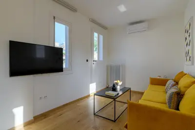 a living room with a yellow couch and a flat screen tv at Meno Suite with Private Terrace - Jaccuzzi, Acropolis View in Athens