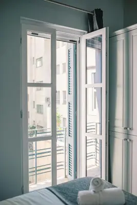 a bedroom with a bed and an open window at Neapolis 1897 Boutique Luxury Rooms in Athens