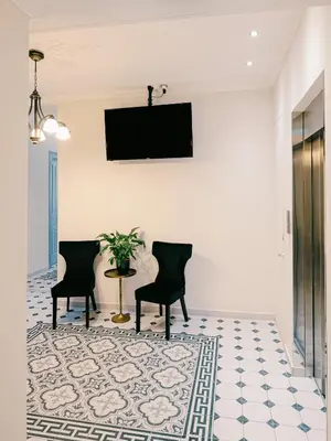 a living room with two chairs and a tv on the wall at Neapolis 1897 Boutique Luxury Rooms in Athens
