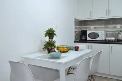 a white kitchen with a white table and chairs at A spacious minimal apatment at Chalandri in Athens