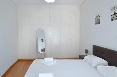 a white bedroom with a bed and a mirror at A spacious minimal apatment at Chalandri in Athens