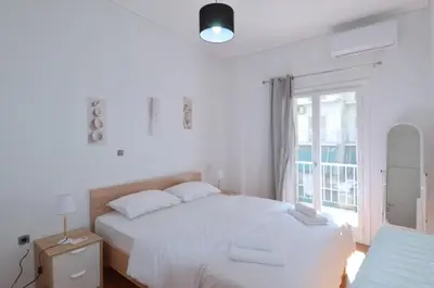 a white bedroom with a large bed and a window at A cozy minimal apartment at Koukaki, Dimitrako... in Athens