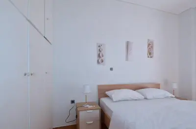 a white bedroom with a bed and a night stand at A cozy minimal apartment at Koukaki, Dimitrako... in Athens