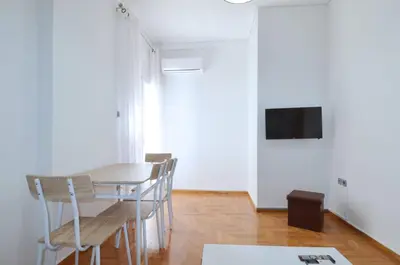 a dining room with a table and chairs and a tv at A cozy minimal apartment at Koukaki, Dimitrako... in Athens
