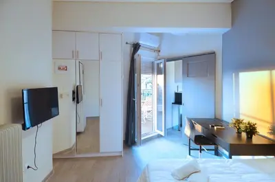 a room with a bed and a desk and a kitchen at A minimal retire at Kypseli with an amazing view in Athens