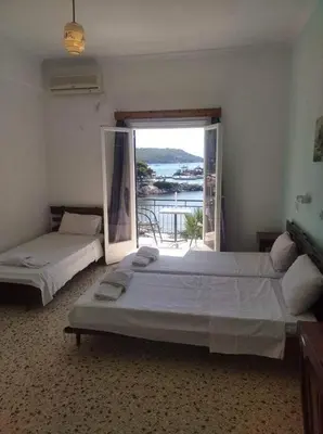 a bedroom with two beds and a large window at Ammoudia Rooms in Agia Marina Aegina
