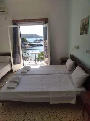 a bedroom with a large bed and a large window at Ammoudia Rooms in Agia Marina Aegina