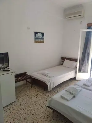 a room with two beds and a television in it at Ammoudia Rooms in Agia Marina Aegina