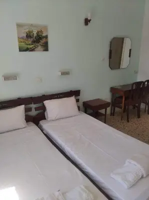 two beds in a room with a table and chairs at Ammoudia Rooms in Agia Marina Aegina