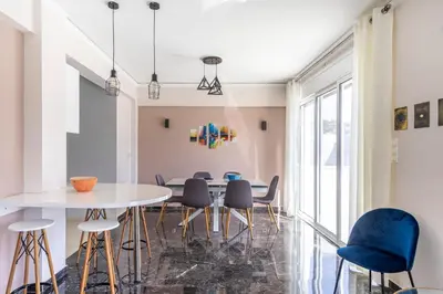 a dining room with a white table and blue chairs at Koukaki Spacious Penthouse with parking for Small Car in Athens
