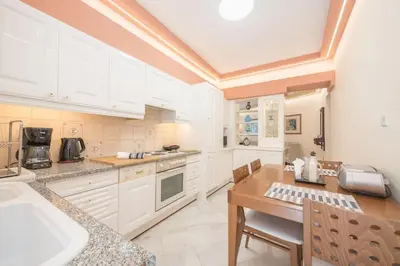 a kitchen with white cabinets and a wooden table at Central 3BR Apartment Next to Panormou Metro! in Athens