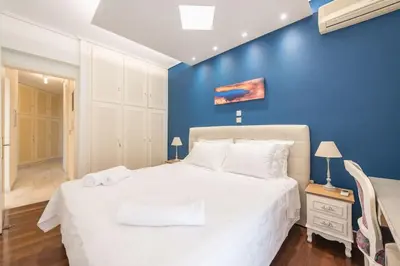 a bedroom with a white bed with a blue wall at Central 3BR Apartment Next to Panormou Metro! in Athens