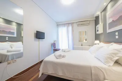 a white bedroom with two beds and a tv at Central 3BR Apartment Next to Panormou Metro! in Athens