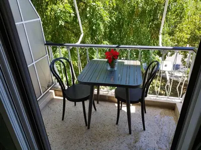 a blue table with a vase of flowers on a balcony at Zeus Apartment in Athens