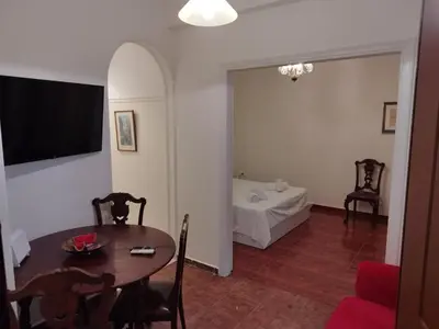 a living room with a table and a room with a bed at Zeus Apartment in Athens
