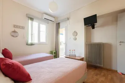 a hotel room with two beds and a television at Heart of Koukaki flat, near Acropolis & Filopappou in Athens