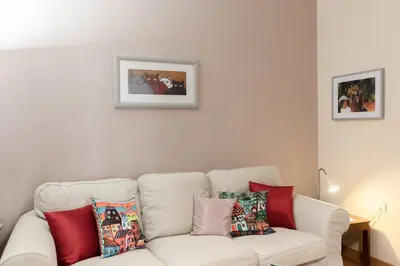 a living room with a white couch with colorful pillows at Heart of Koukaki flat, near Acropolis & Filopappou in Athens