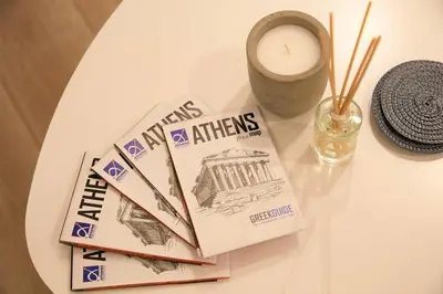 a table with a book and a candle and a vase at Athelia Athens in Athens
