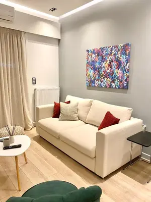 a living room with a white couch and a painting at Athelia Athens in Athens