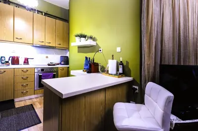 a kitchen with green walls and a counter with a chair at Premium GaLeRia 4A in Athens